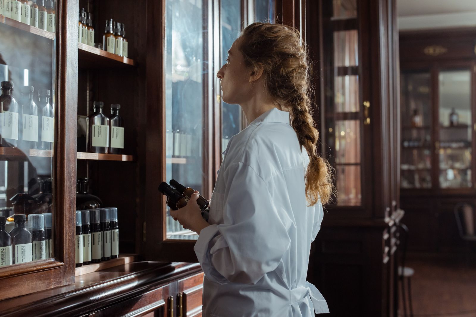 Pharmacienne examinant les flacons rangés sur les étagères d’une officine.
