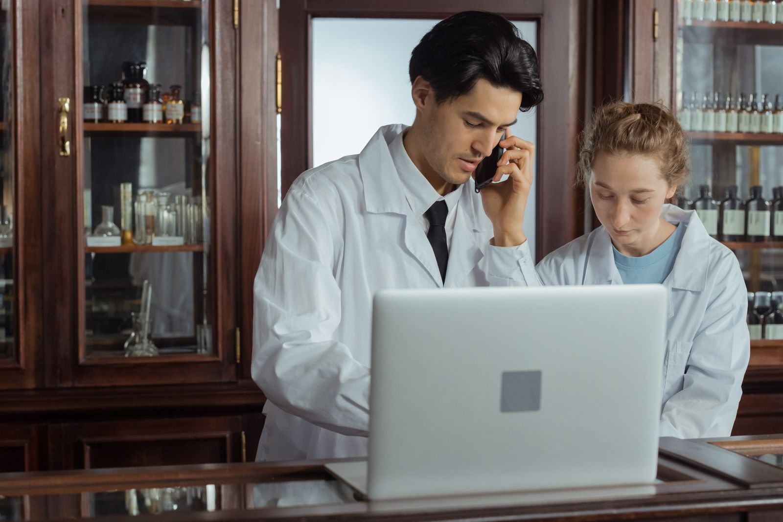 Deux pharmaciens travaillant sur un ordinateur portable au comptoir d’une officine.